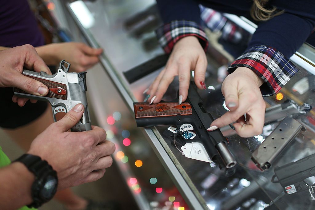 A customer compares handguns before buying one as a Christmas present at the National Armory gun store on December 23, 2015 in Pompano Beach, Florida.(Photo by Joe Raedle/Getty Images)
